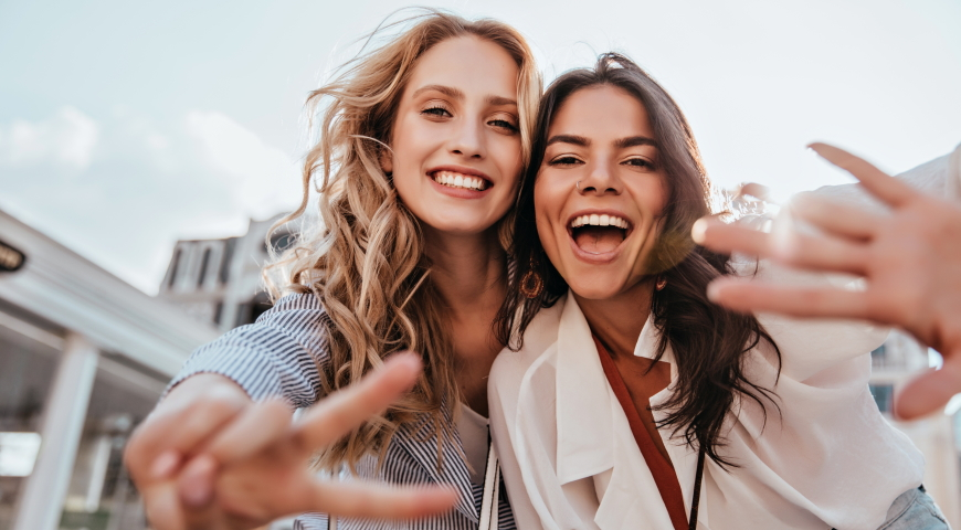 Lovable caucasian girls expressing positive emotions to camera. Outdoor photo of refined sisters posing on sky background.